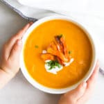 Child Grabbing Bowl of Carrot and Orange Soup