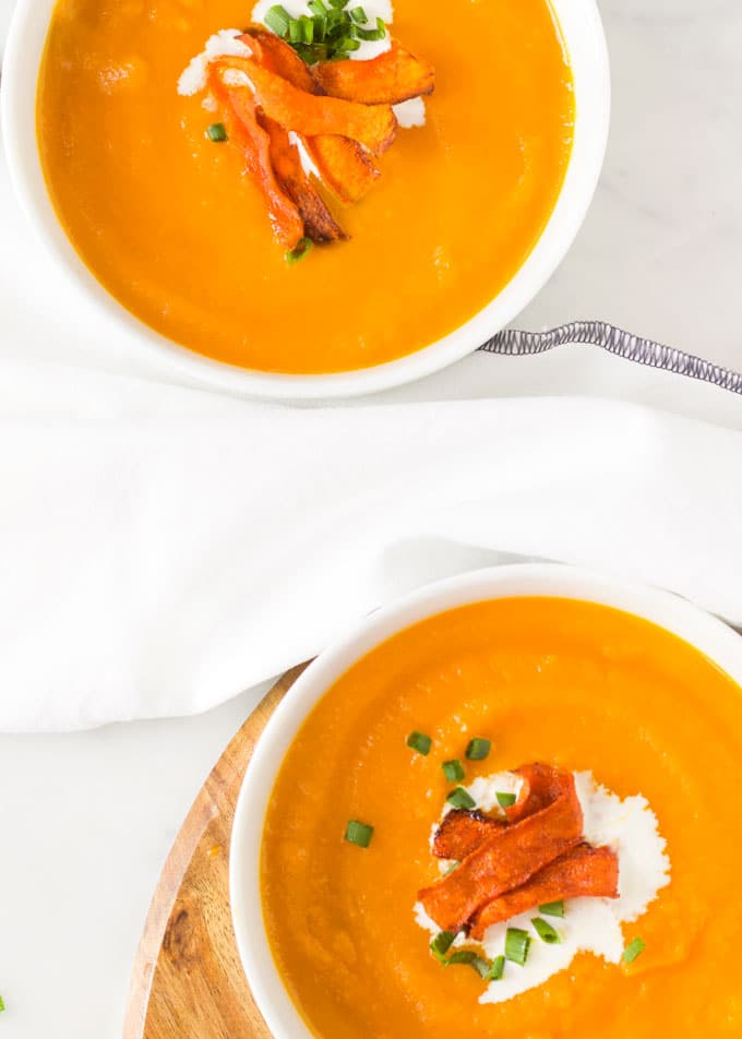 Carrot and Orange Soup in Bowls Topped with Roasted Carrot Strips, Cream and Chives