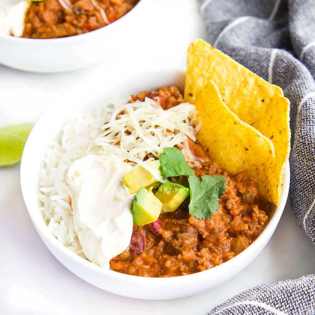 Chilli Con Carne in Bowl with Rice and Tortilla Chips topped with Avocado, Cheese and Sour Cream.