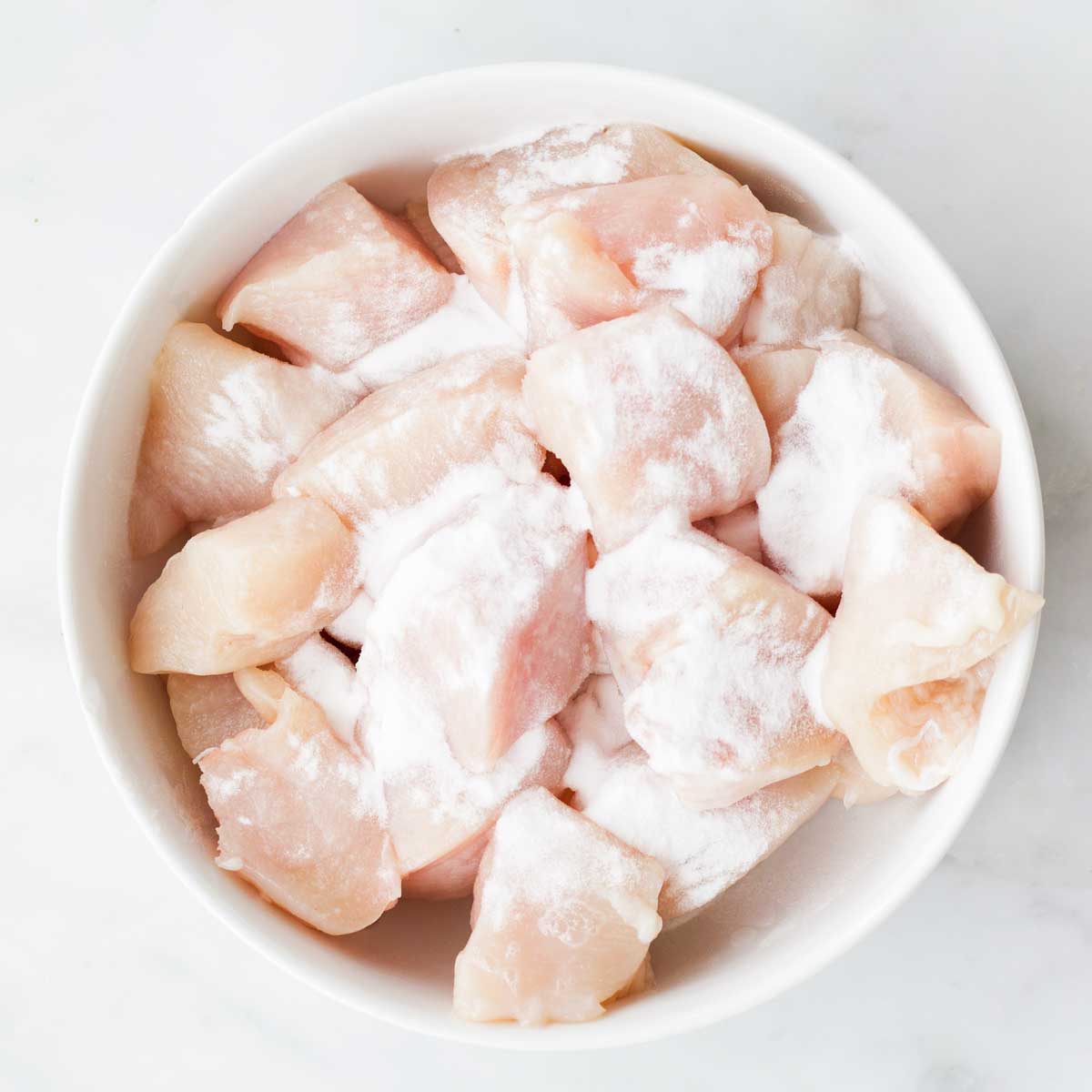 Bowl of Chicken Breast Chunks with Baking Soda Sprinkled On Top.