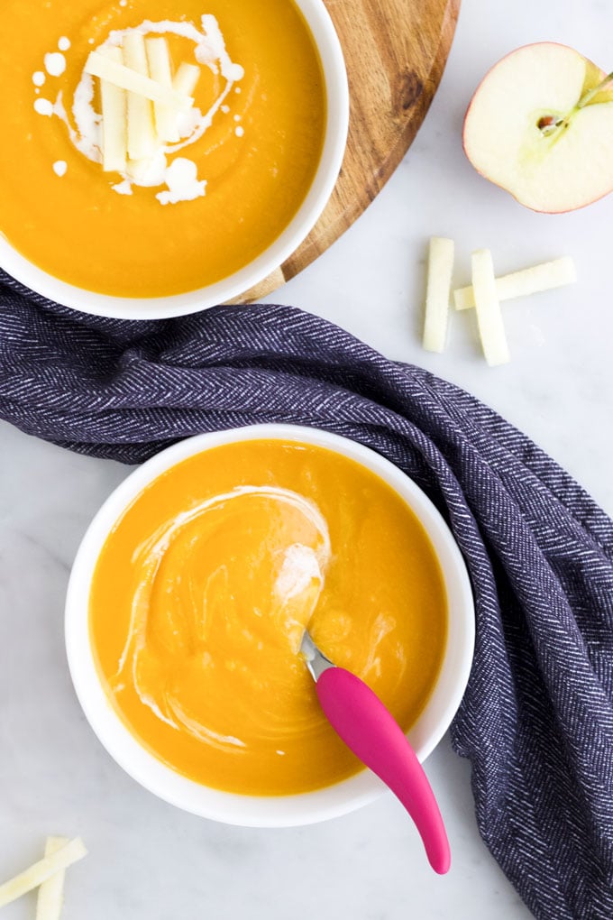 Butternut Squash and Apple Soup in Bowls. Topped with Cream and Apple Matchsticks.