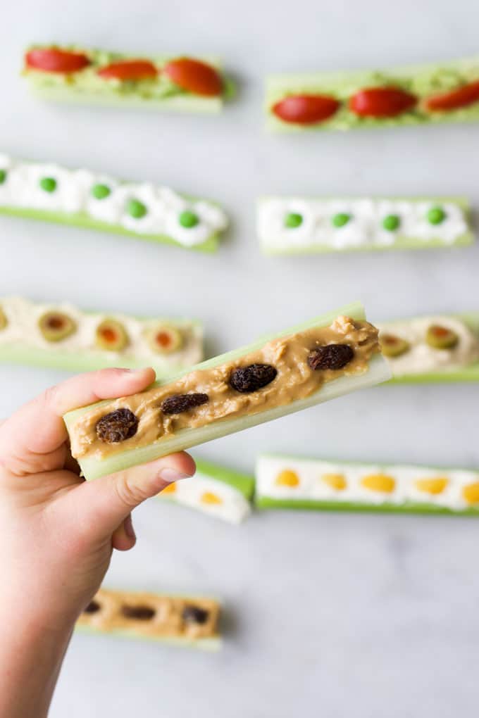 Child Holding Peanut Butter and Raisin Ants on a Log