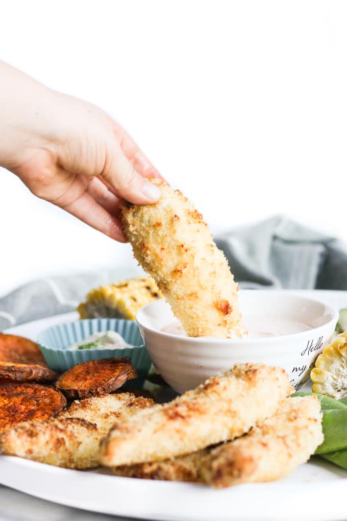 Hand Dipping Coconut Chicken Tender into Dip