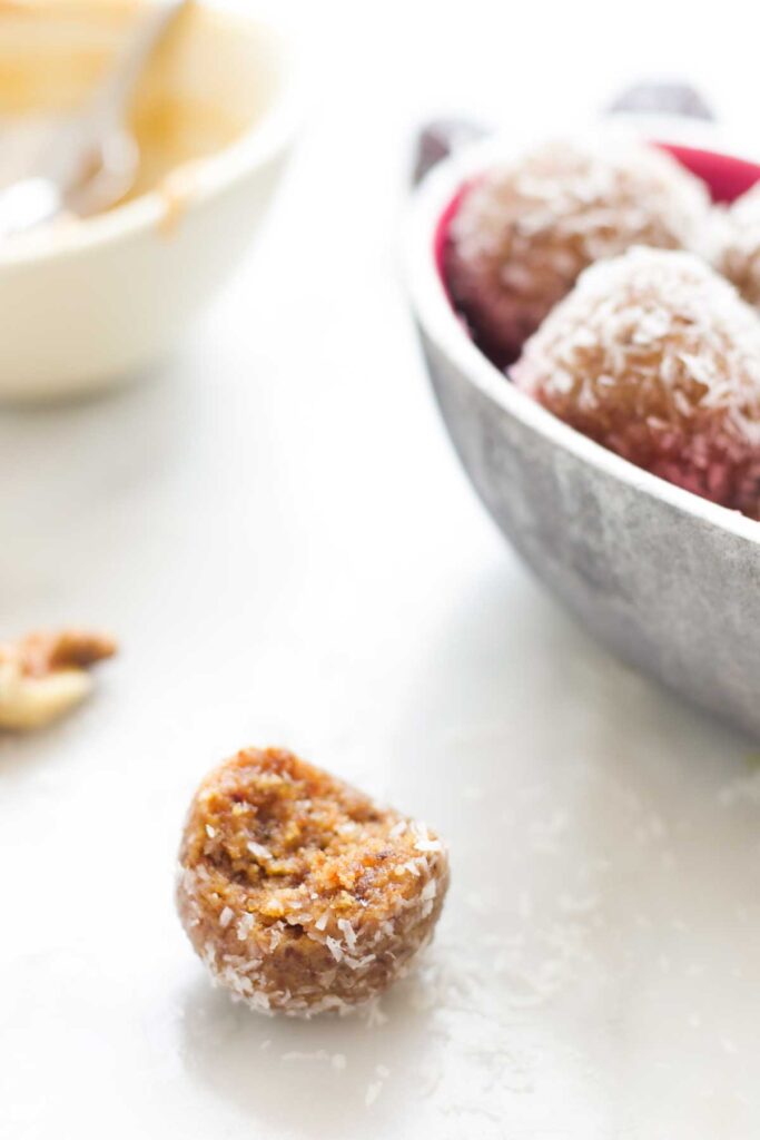 Close Up Side Shot of a Nut Ball With Bite Removes. Bowl of Nut Balls and Ingredients in Background