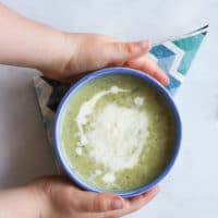 Child Grabbing Bowl of Courgette Soup (Zucchini)