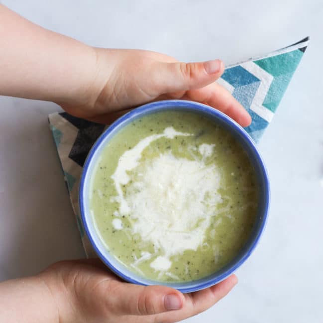 Child Grabbing Bowl of Courgette Soup (Zucchini)