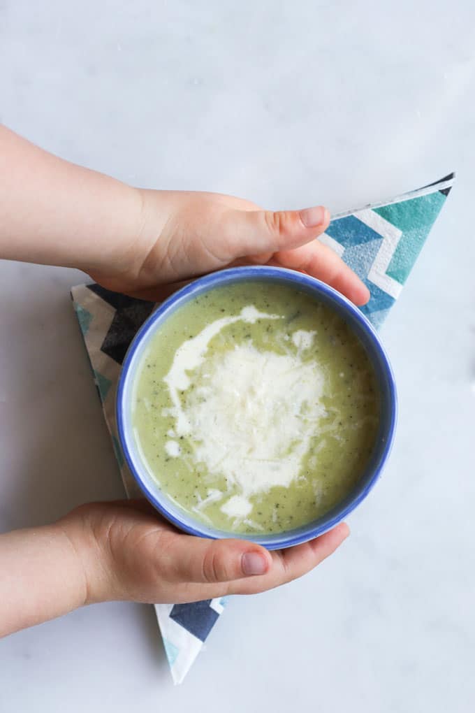 Child Grabbing Bowl of Courgette Soup (Zucchini)