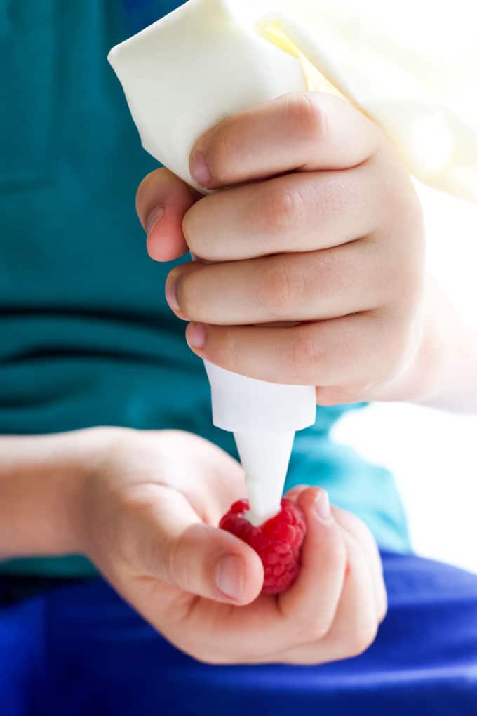 Child Filling Raspberry with Yoghurt