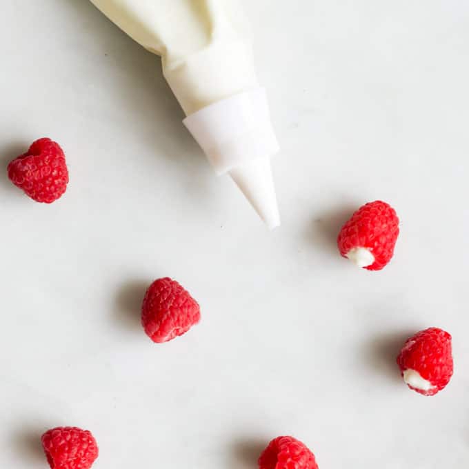 Piping Bag Filled With Yoghurt Next To Raspberries