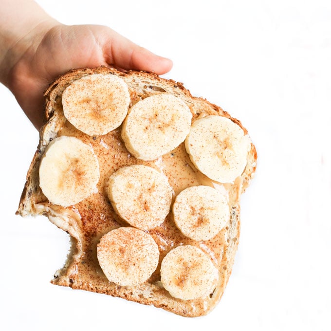 Child Holding Toast Topped with Nut Butter and Banana