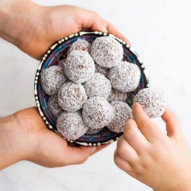 Child Grabbing a Sweet Potato Truffle from Bowl