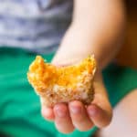 Child Holding Sweet Potato Croquette with Bite Out