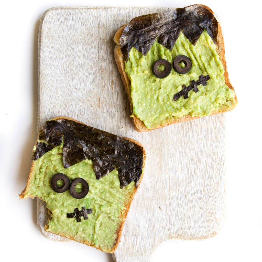Two Slices of Avocado Toast with Frankenstein Face Made with Yaki Nori and Black Olives