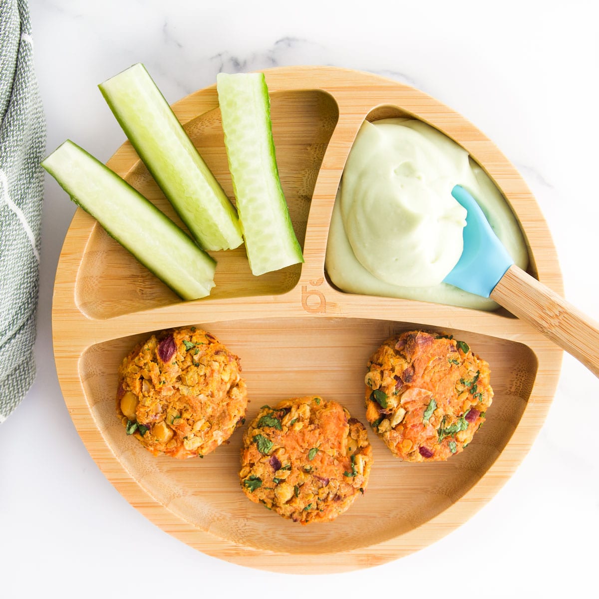 Sweet Potato Chickpea Cakes on Baby/Toddler Bamboo Plate Served with Avocado Dip and Cucumber Sticks.