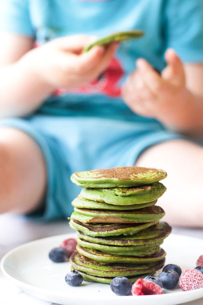 Child Eating Spinach Pancake from Stack