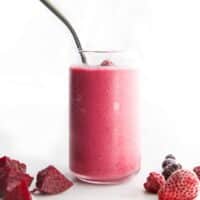 Vibrant Pink Beet Smoothie in Tall Glass with Beets and Berries in the Foreground