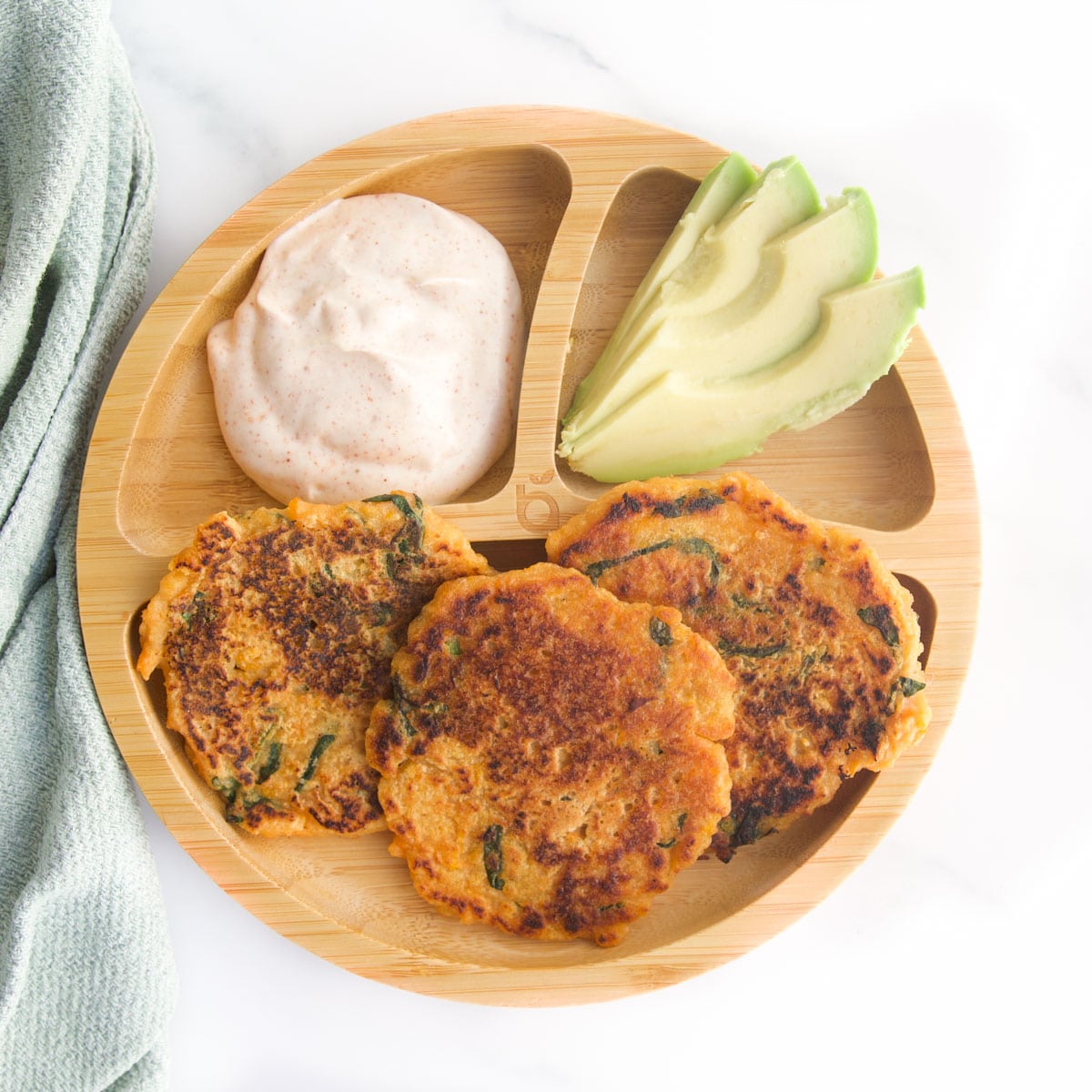 Baby Bamboo Plate with Three Sections. The Main Section has Three Small Lentil Pancakes, One Section has Sliced Avocado and the Last Has A Smoked Paprika Yogurt Dip.