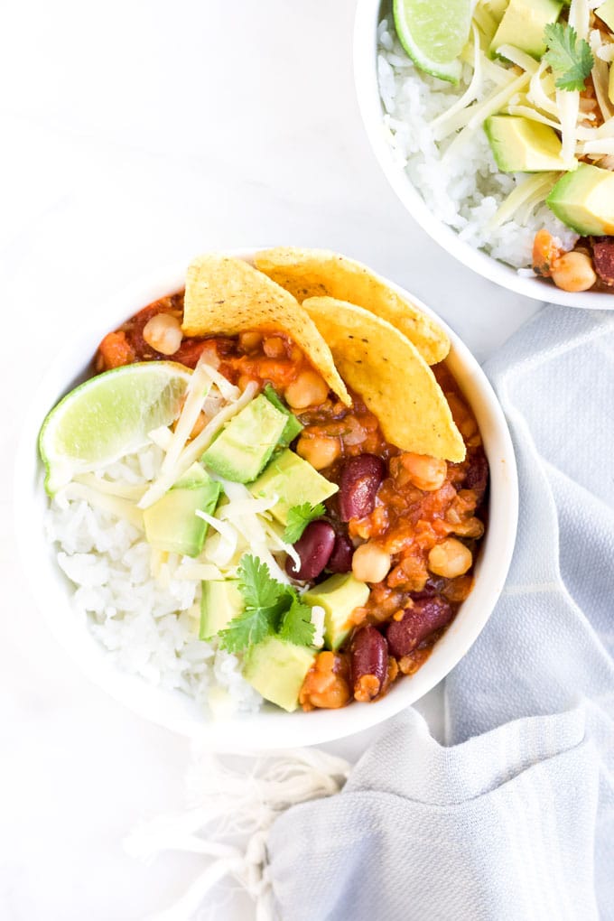 Vegetarian Chilli in Bowl Topped with Grated Cheese, Avocado , Corn Chips and LIme Wedge