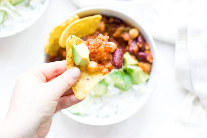 Child Holding Corn Chip Topped with Vegetarian Chilli