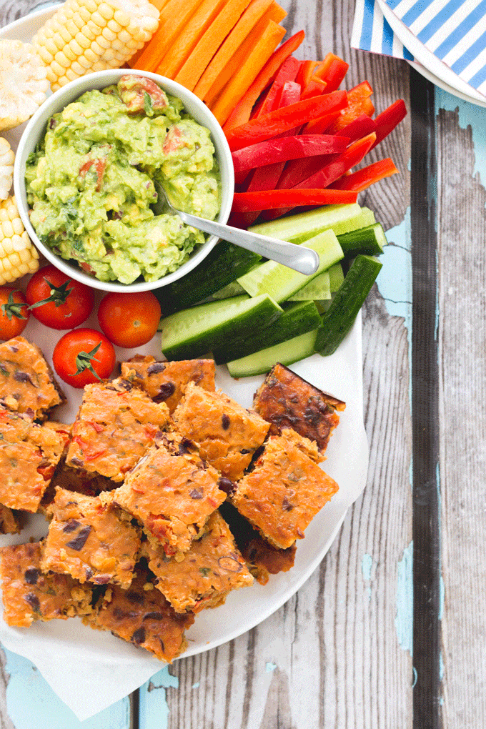 Squares of Veggie Lentil Slice on White Plate Along with Sliced Vegetables and Guacamole. 