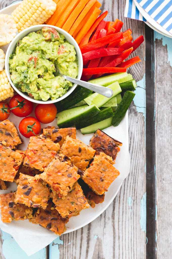 Squares of Veggie Lentil Slice on White Plate Along with Sliced Vegetables and Guacamole.