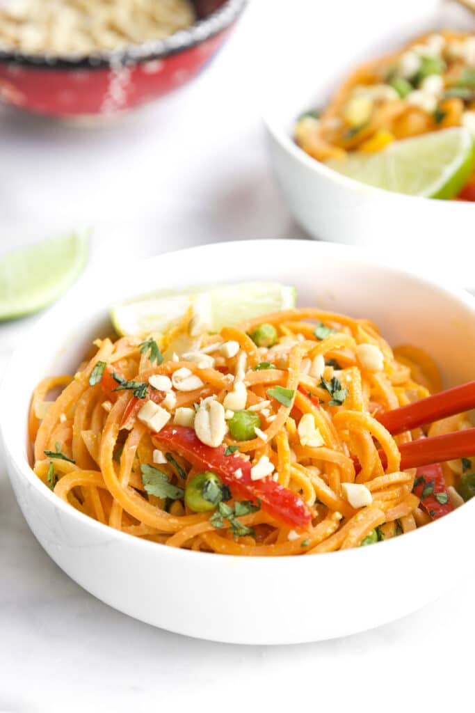 Close up Shot of Sweet Potato Noodles in White Bowl Served with Red Chop Sticks. Second Bowl Cut of In Background