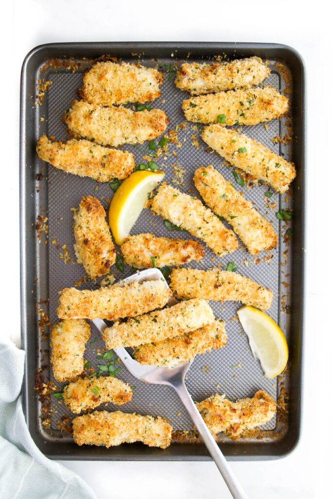 Cooked Fish Goujons  on Baking Tray with Lemon Wedges