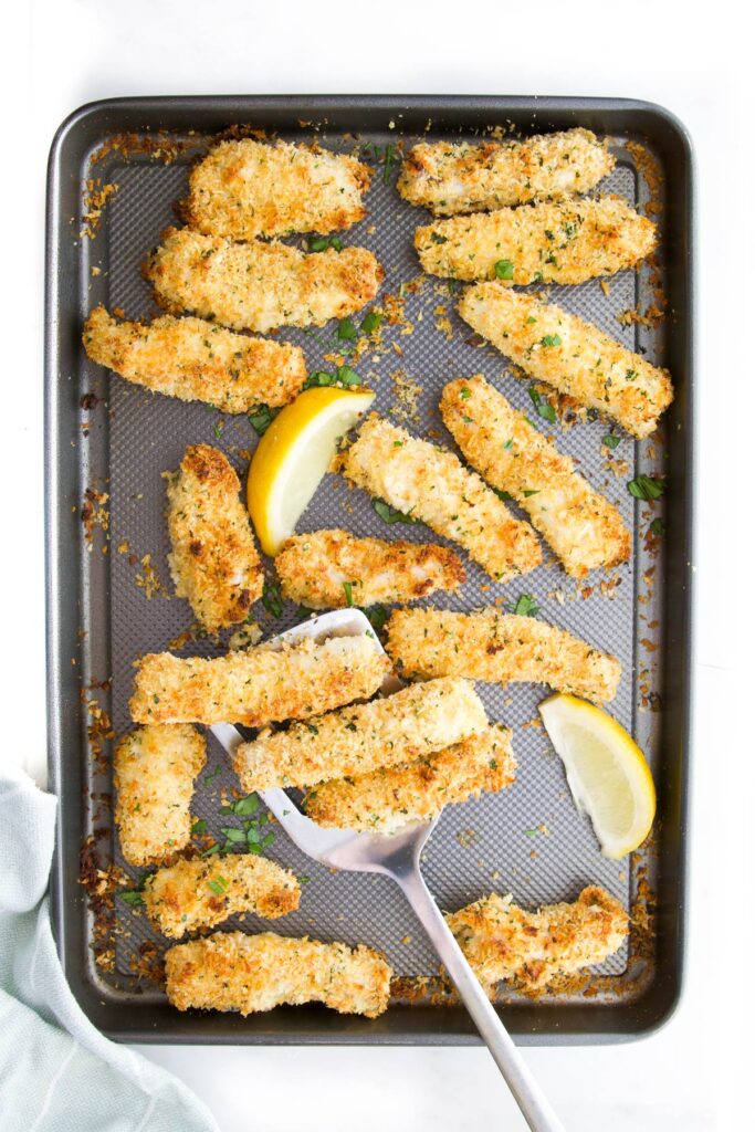 Cooked Fish Goujons on Baking Tray with Lemon Wedges