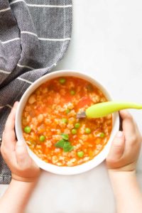 Child Holding a Bowl of Minestrone Soup