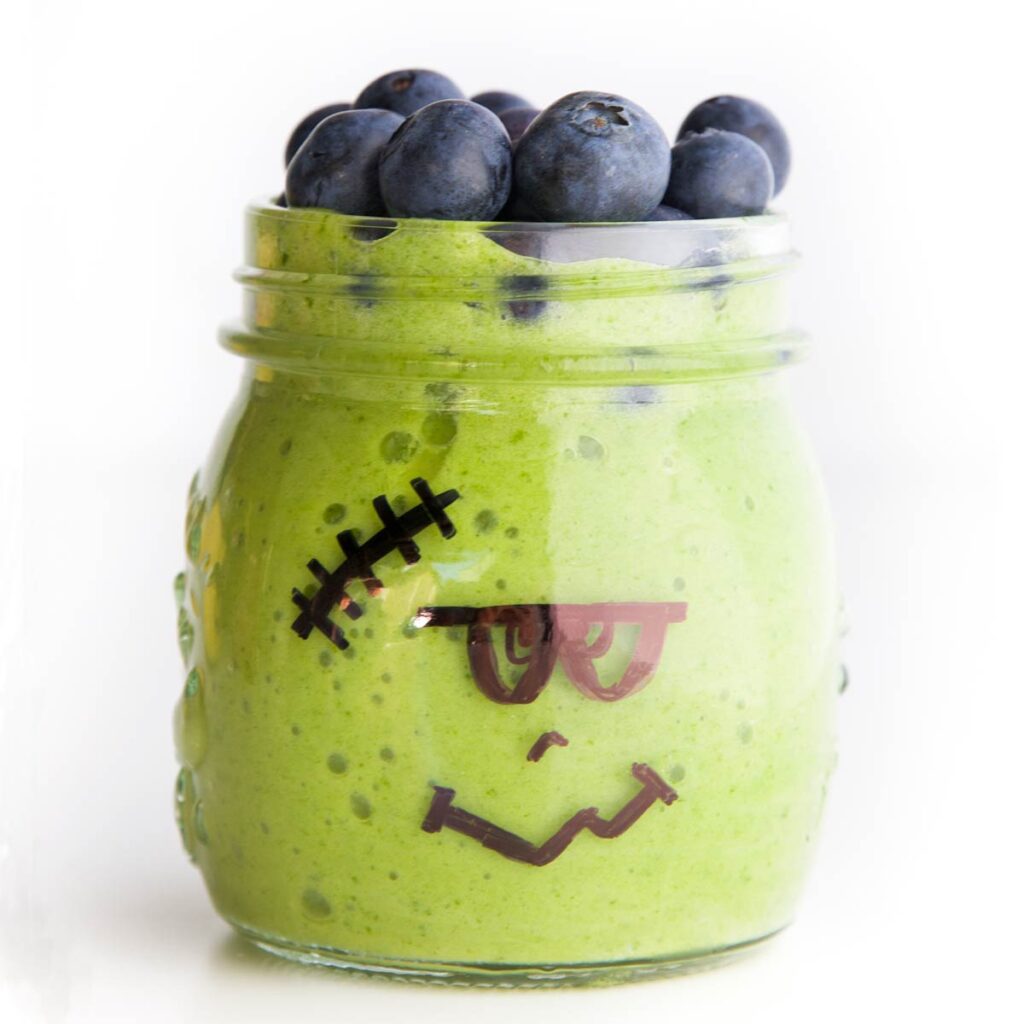 Frankenstein Smoothie (Glass Jar with Frankestein Face Drawn on Filled with Green Smoothie and Topped with Blueberries