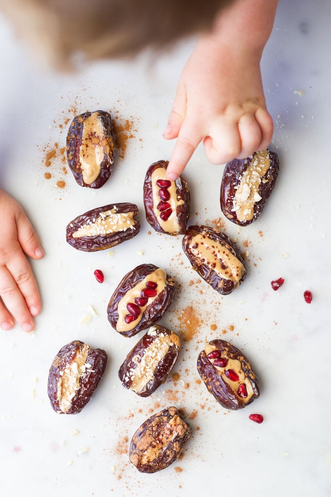 Toddler choosing stuffed date. Pointing to peanut butter stuffed date with pomegranate. 