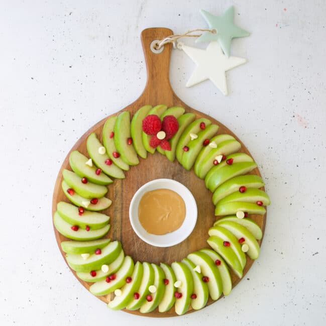Apple Slices on Round Board to Represent a Wreath. Topped with Pomegranate Seeds.