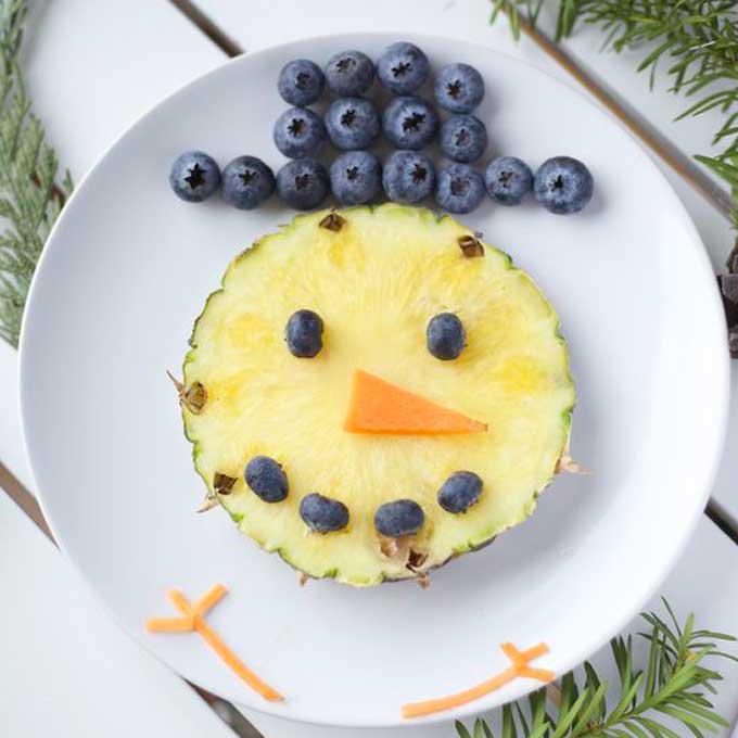 Bonhomme de neige fait à partir d'un visage d'ananas et d'un chapeau de myrtilles