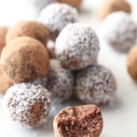 Bliss balls sitting on top of each other. One ball at front with bite out.