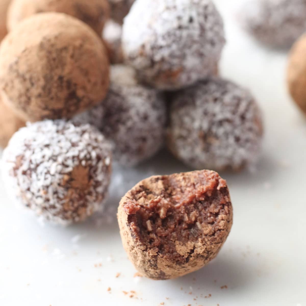 Close Up Shot of Cherry Bliss Ball with Bite Removed and Whole Balls in Background. 