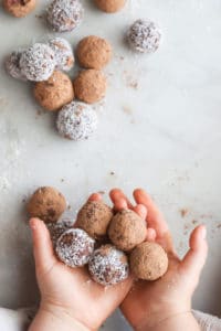 Child holding cherry bliss balls covered in cocao and coconut