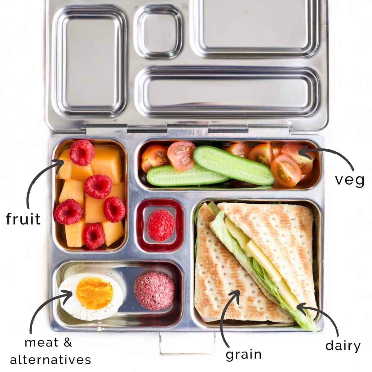 Metal Bento Lunchbox Filled with Cheese Sandwich, Vegetables, Berries, Mango, Egg and Raspberry Oat Ball.