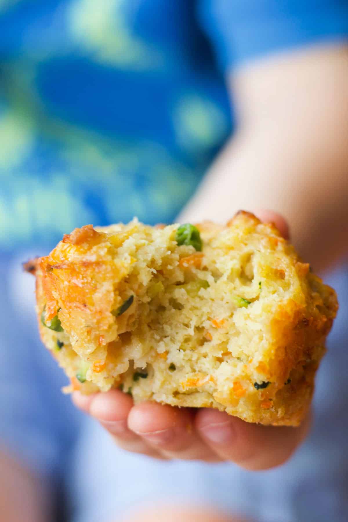 Child Holding Vegetable Savoury Muffin with Bite Removed. 