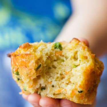 Child Holding Savoury Muffin with Bite Out of it.