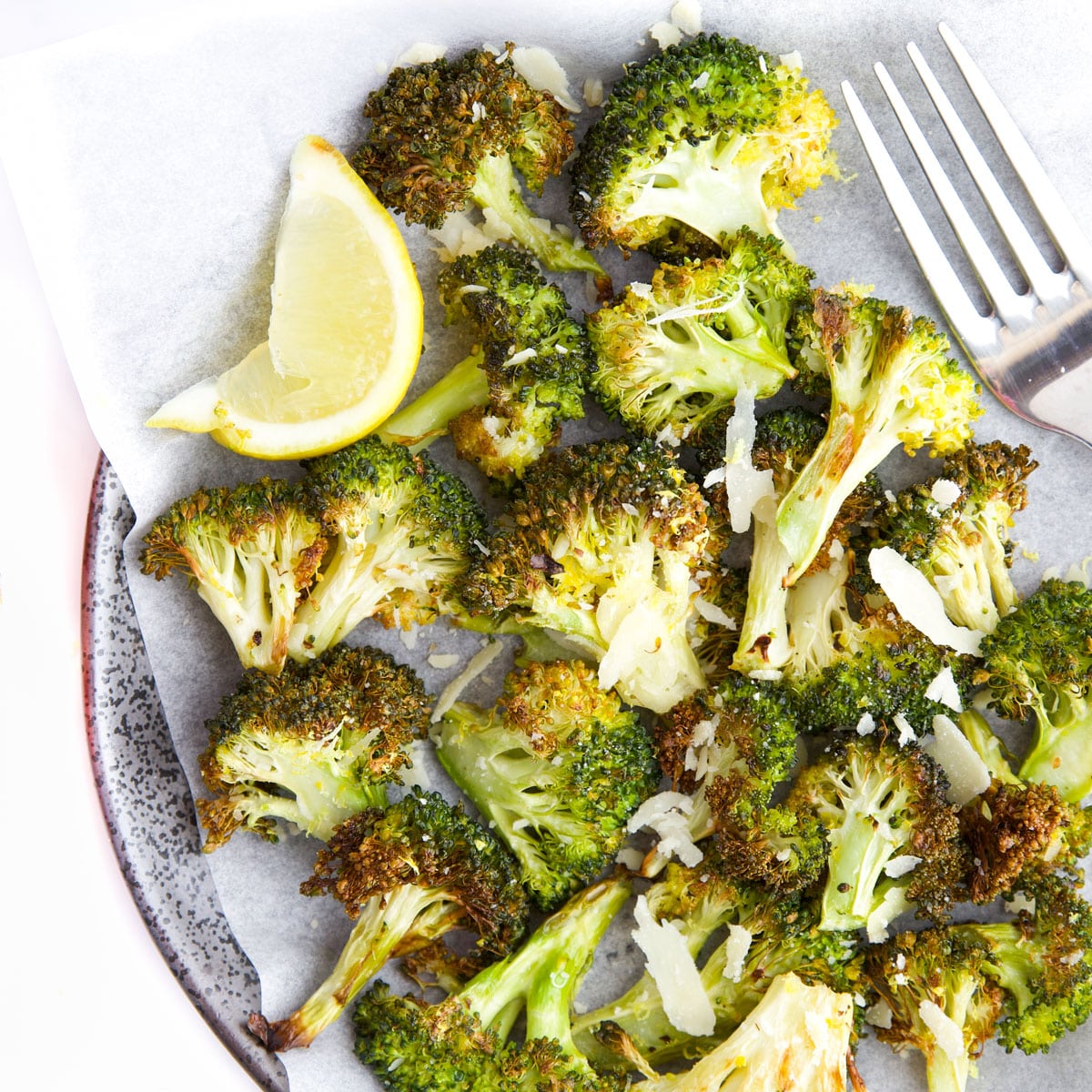 Roasted Broccoli on Plate with Lemon Wedge and Fork.