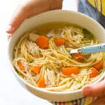 Child Holding Bowl of Slow Cooker Chicken Noodle Soup