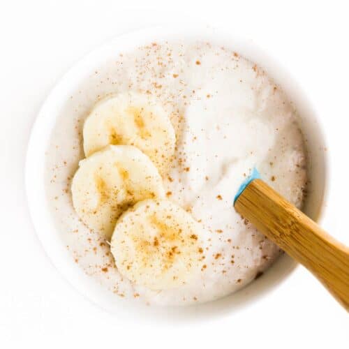 Banana Yogurt in White Bowl Topped with 3 Slices of Banana.