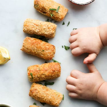 Toddler Hands Next to Line of Salmon Croquettes