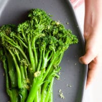 Child holding Plate of Sautéed Broccolini topped with Lemon Zest