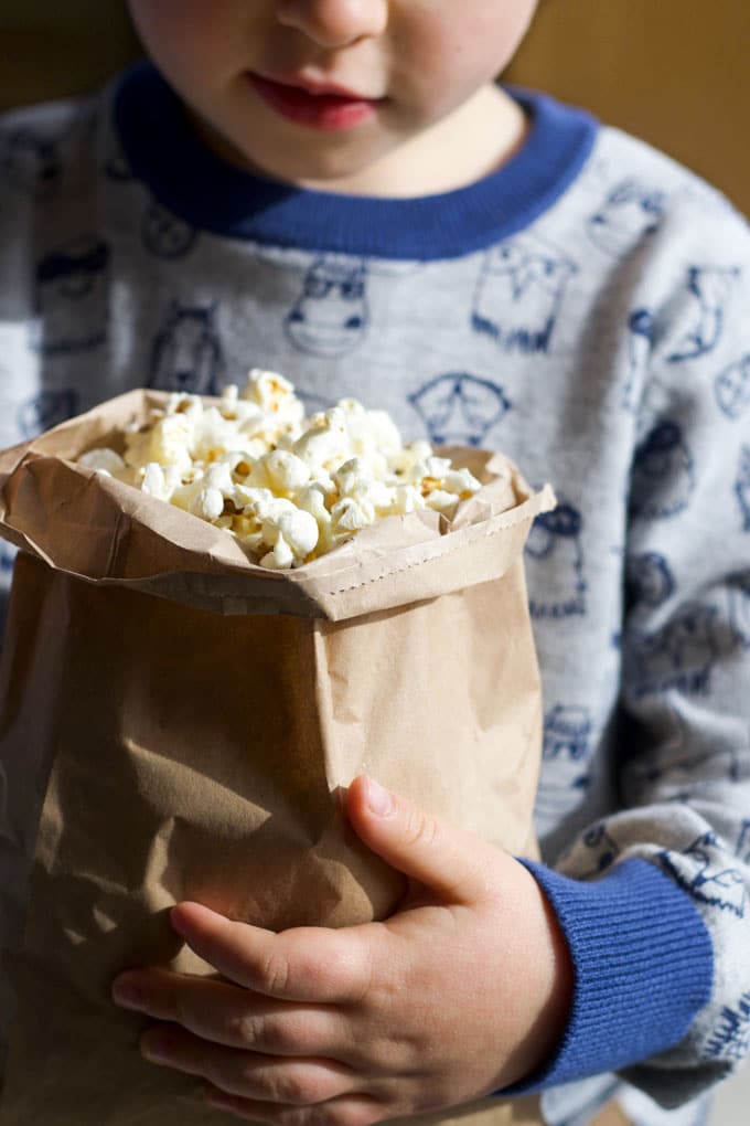 Child Holding Brown Bag of Popcorn