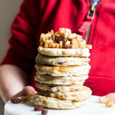 Child Holdin Stack of Apple Pancakes Topped with Cinnamon Apples