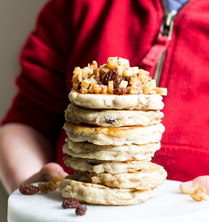 Child Holdin Stack of Apple Pancakes Topped with Cinnamon Apples
