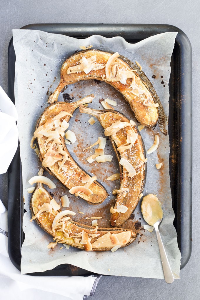 Baked bananas on Baking Tray Topped with Peanut Butter and Coconut