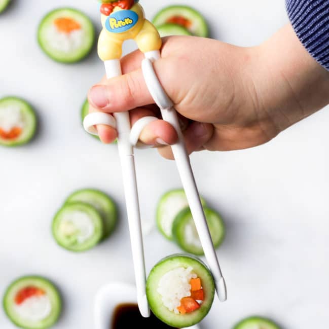 Child's Hand Picking Up Cucumber Sushi with Chop Sticks