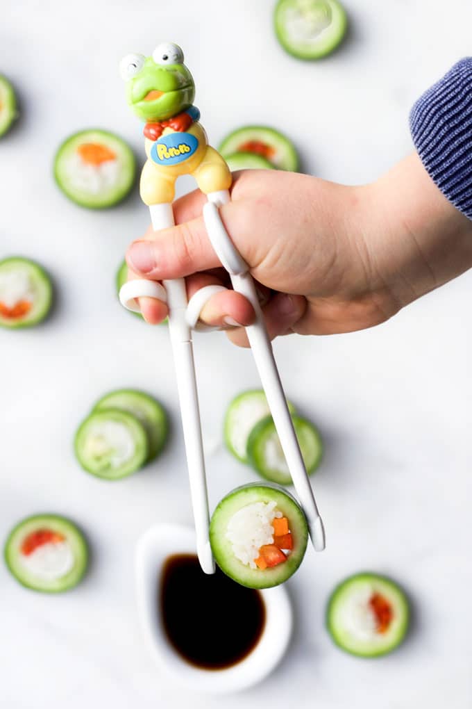 Child's Hand Picking Up Cucumber Sushi with Chop Sticks